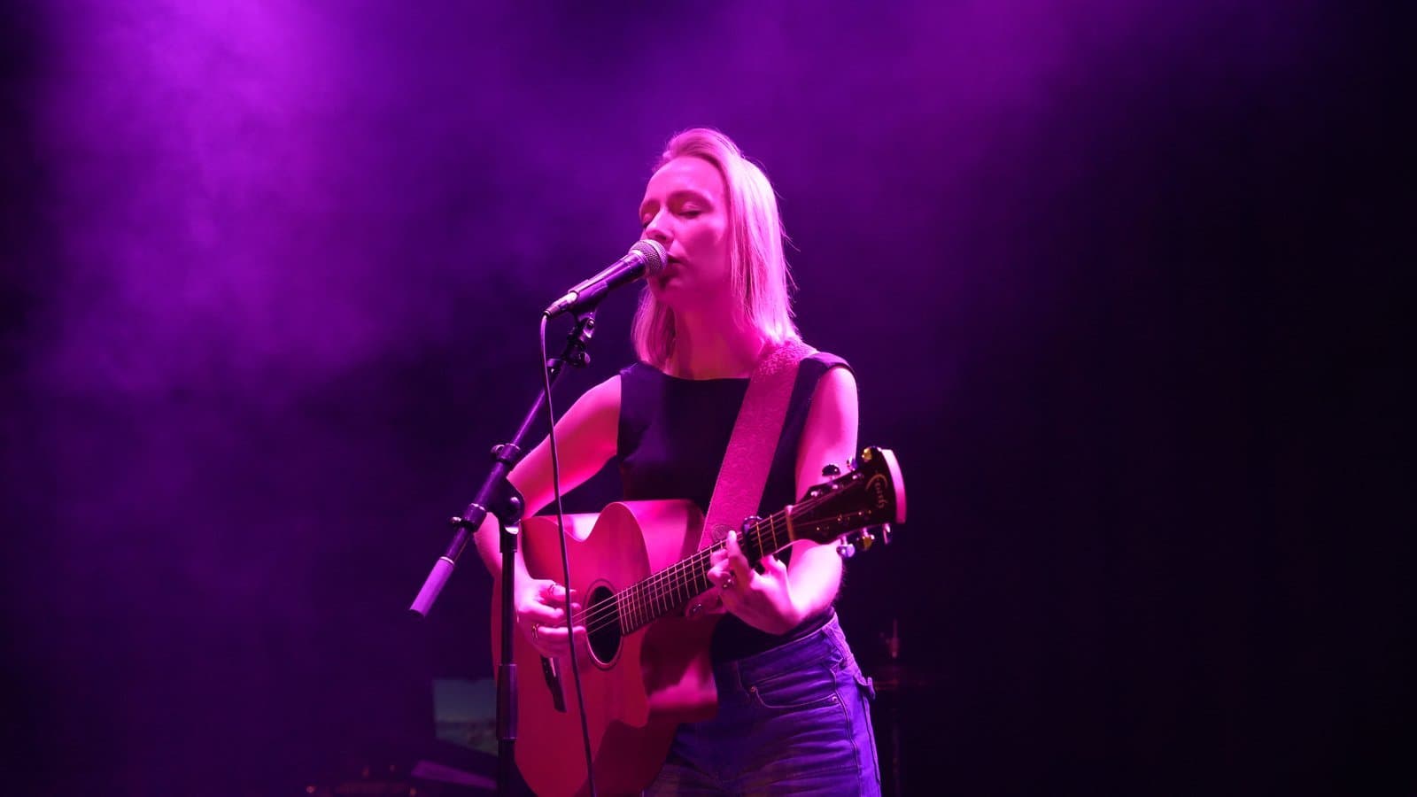 Singer-songwriter bathed in magenta stage light