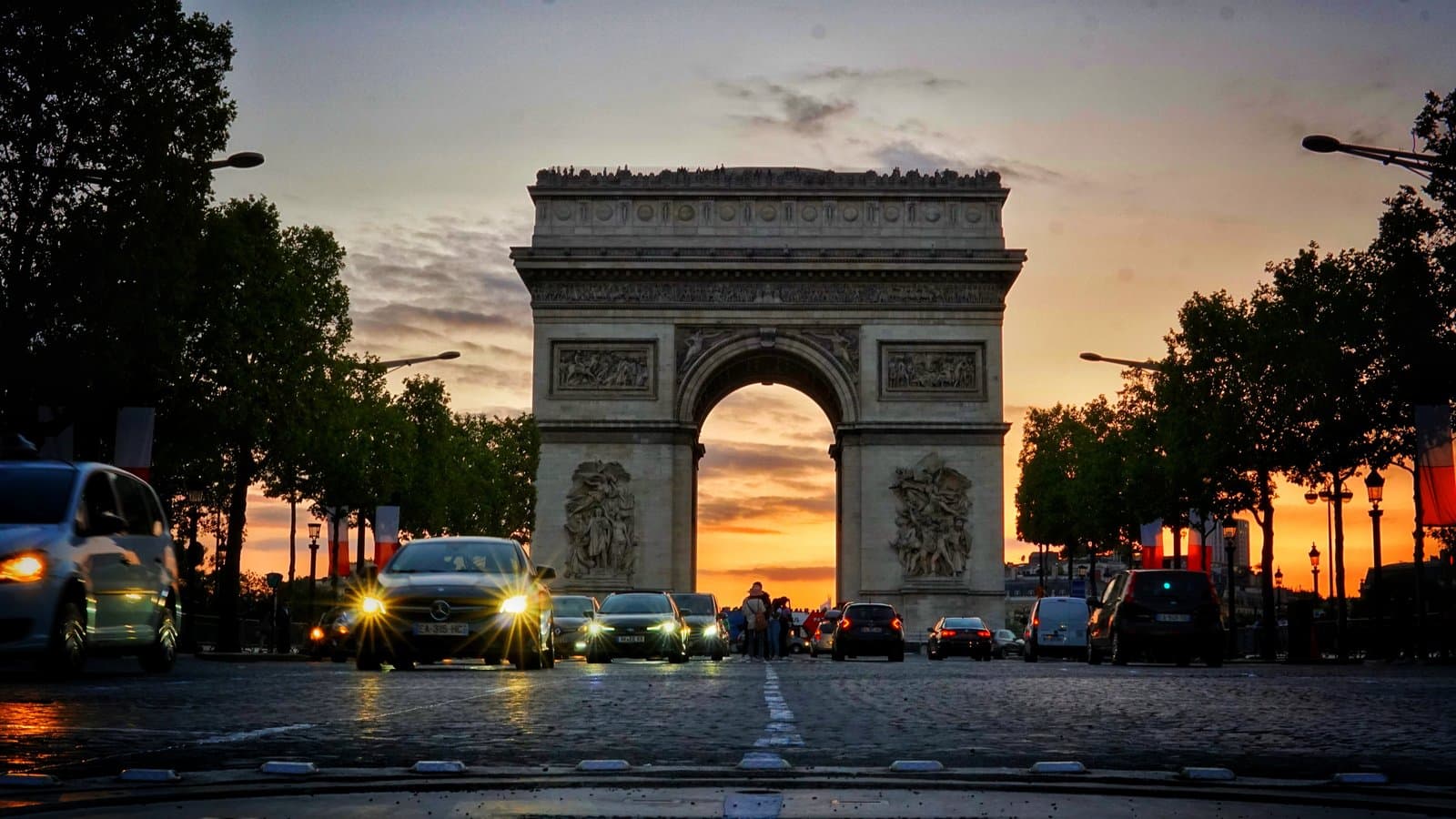 Arc de Triomphe glowing under a dramatic sunset on the Champs-Élysées